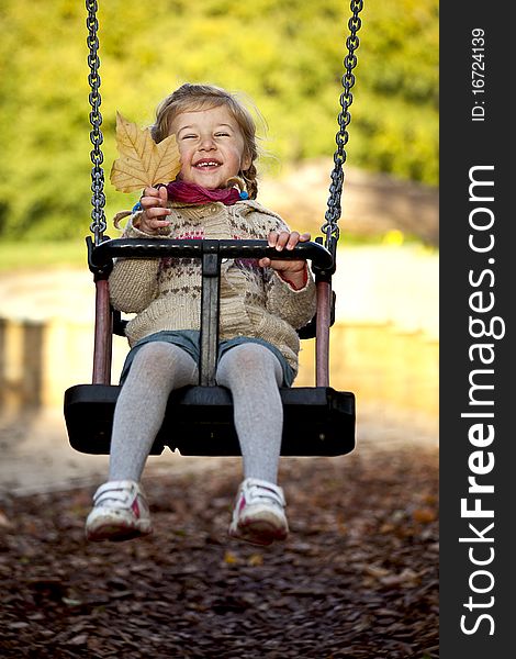 Little happy girl swinging on the playground in the park. Little happy girl swinging on the playground in the park