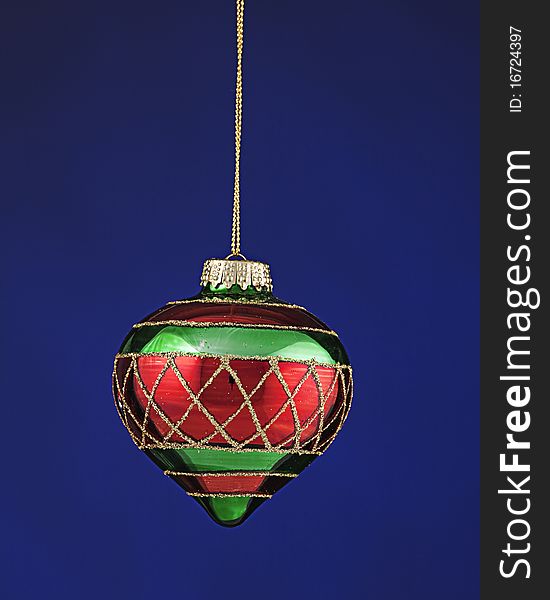 A red and green Christmas tree ornament isolated against a dark blue background. A red and green Christmas tree ornament isolated against a dark blue background.