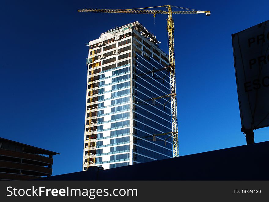 Almost completed tower building with yellow crane on blue sky. Almost completed tower building with yellow crane on blue sky