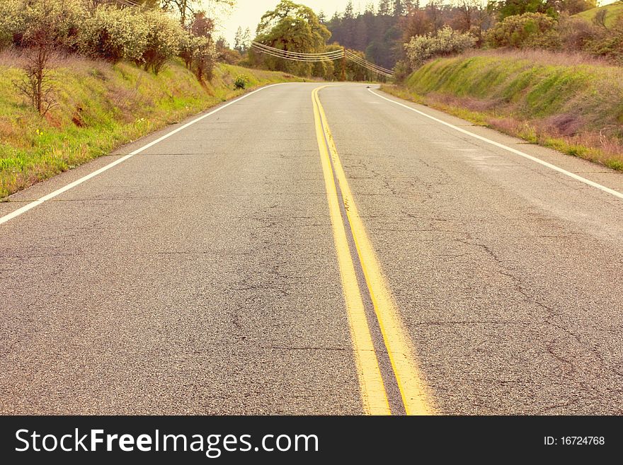 Empty roadway leading through the wooded countryside.