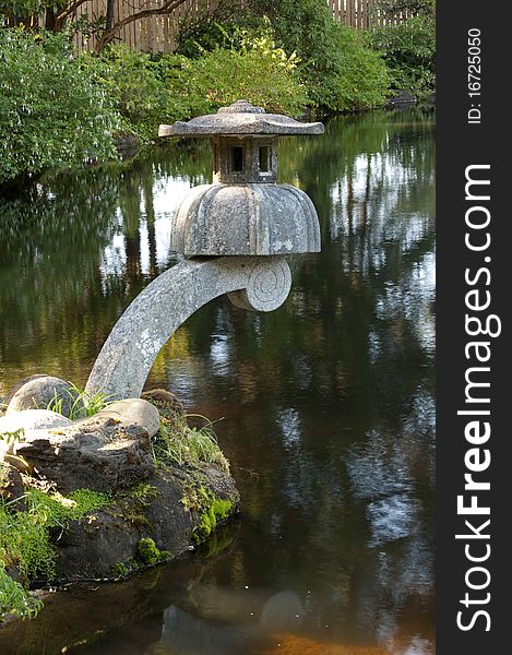 A zen cement lantern decoration above a garden pond. A zen cement lantern decoration above a garden pond.