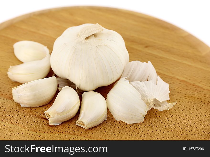 Garlic on a wooden plate. Isolated on a white background