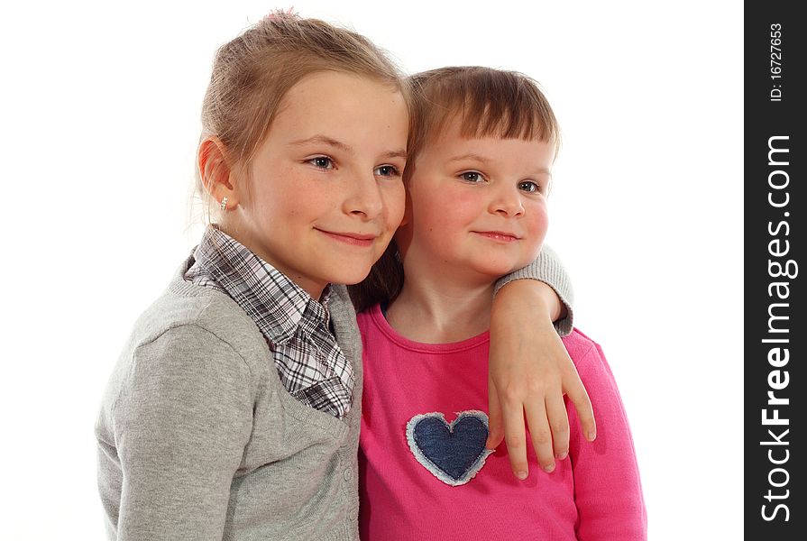 Two cute young sisters posing together in a studio