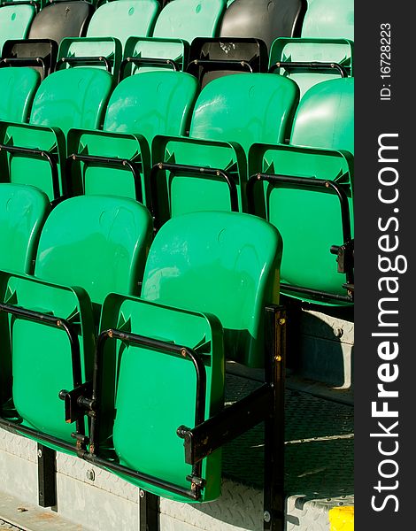 Rows of green plastic fold up stadium seats located in a football ground. Rows of green plastic fold up stadium seats located in a football ground