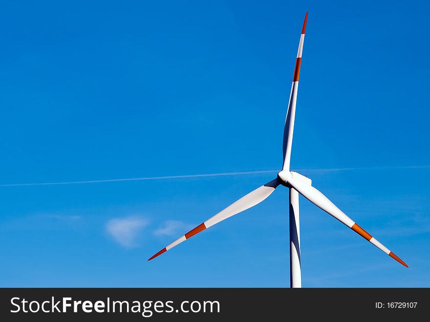 Large wind turbine turns against a blue sky