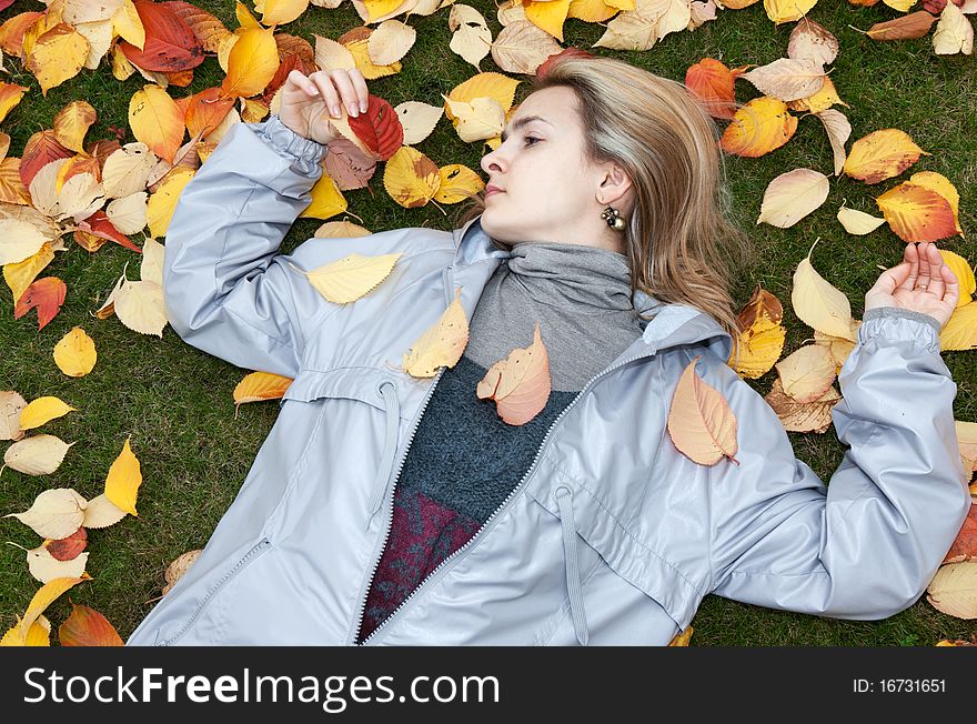 Beautiful girl rests upon autumn sheet and green herb