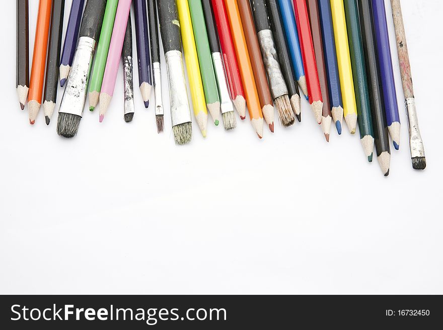 Paint brushes and color pencils isolated on white