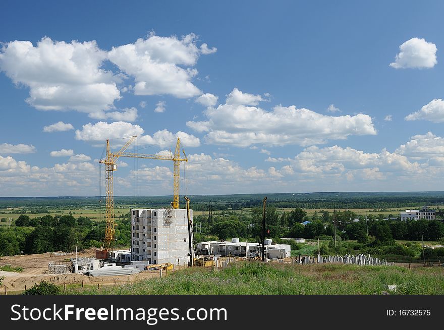 Panoramic view of the apartment building under construction against endless green fields. Panoramic view of the apartment building under construction against endless green fields