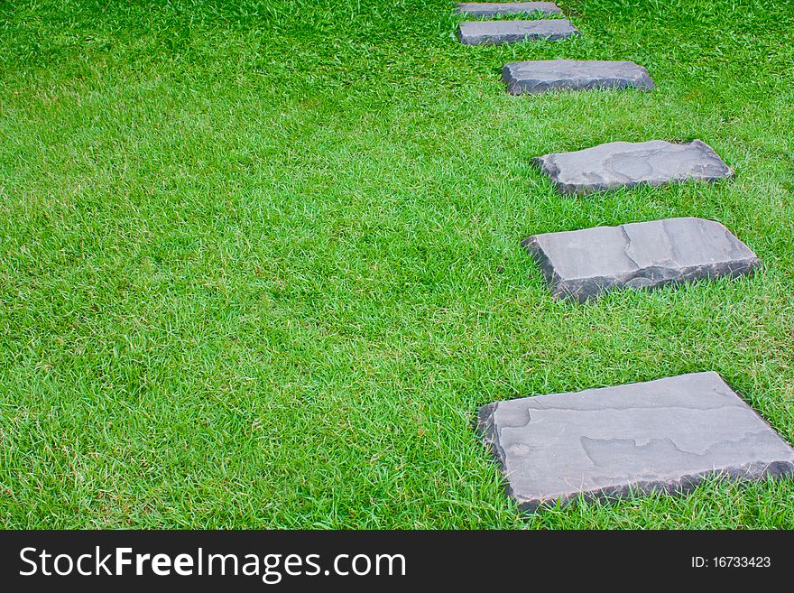 Stone alley as walk way on green grass. Stone alley as walk way on green grass.