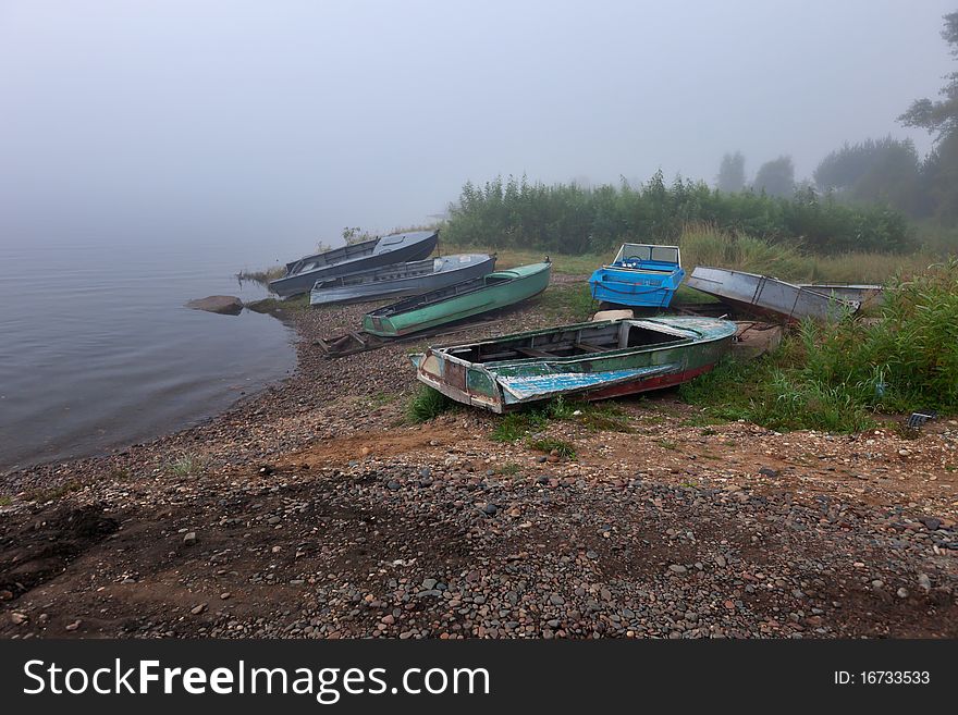 Old boats at the foggy riverbank. Siberia, Enisey, Russia.