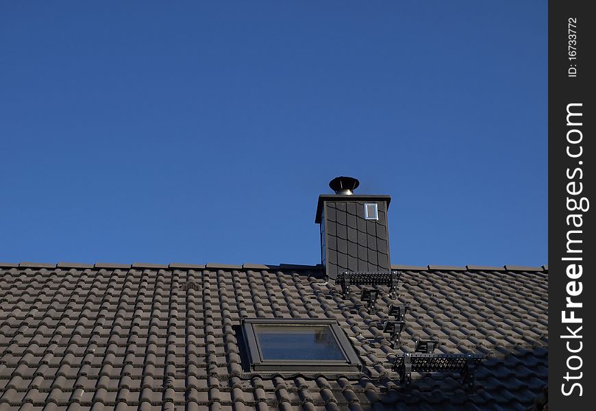 Gray roof and chimney in the blue sky