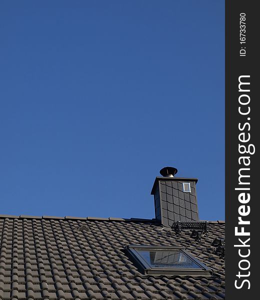 Gray roof and chimney in the blue sky