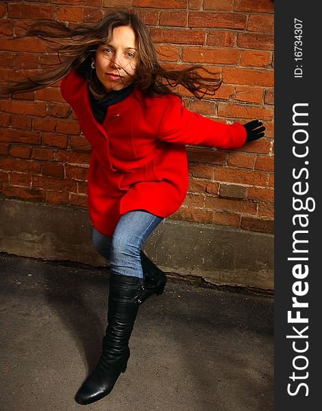 Girl in a red overcoat on a background a brick wall. Girl in a red overcoat on a background a brick wall