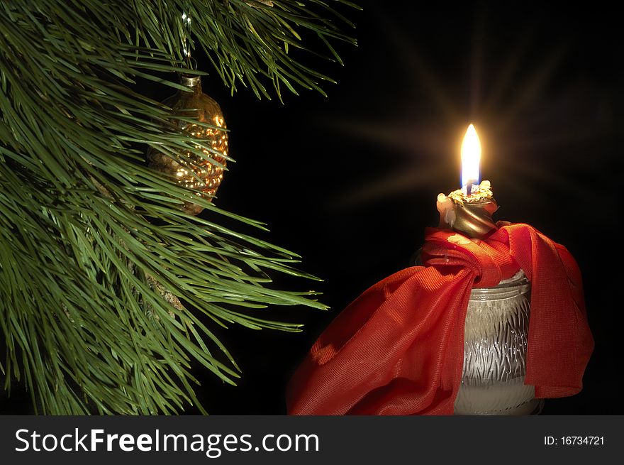 Burn red candle with green pine branch on dark background. Burn red candle with green pine branch on dark background