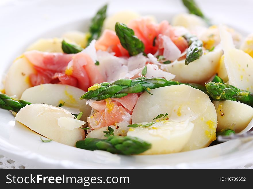 Prosciutto with asparagus and potatoes on white plate