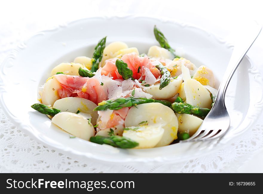 Prosciutto with asparagus and potatoes on white plate