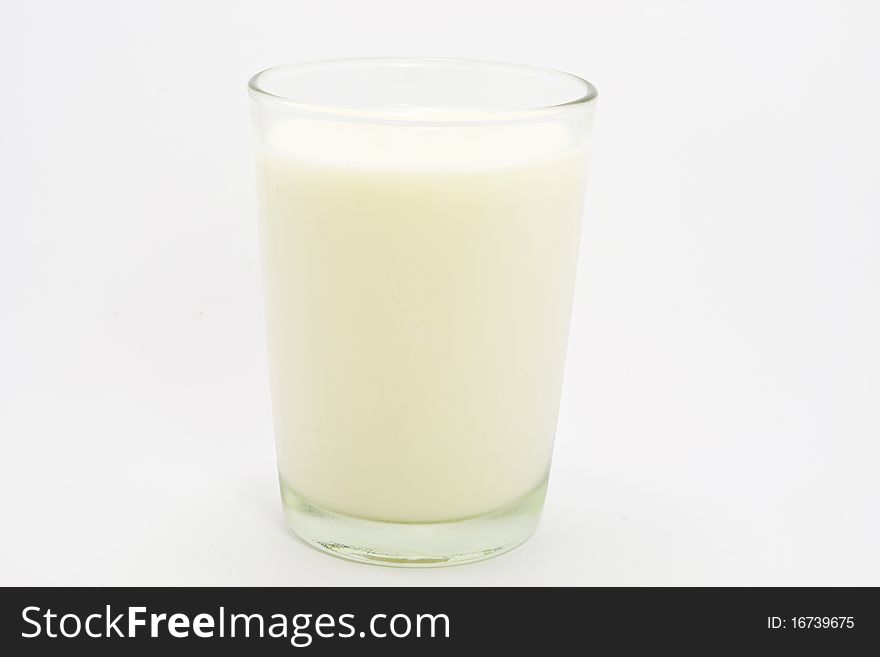 Creamy milk in a transparent glass and on white background.