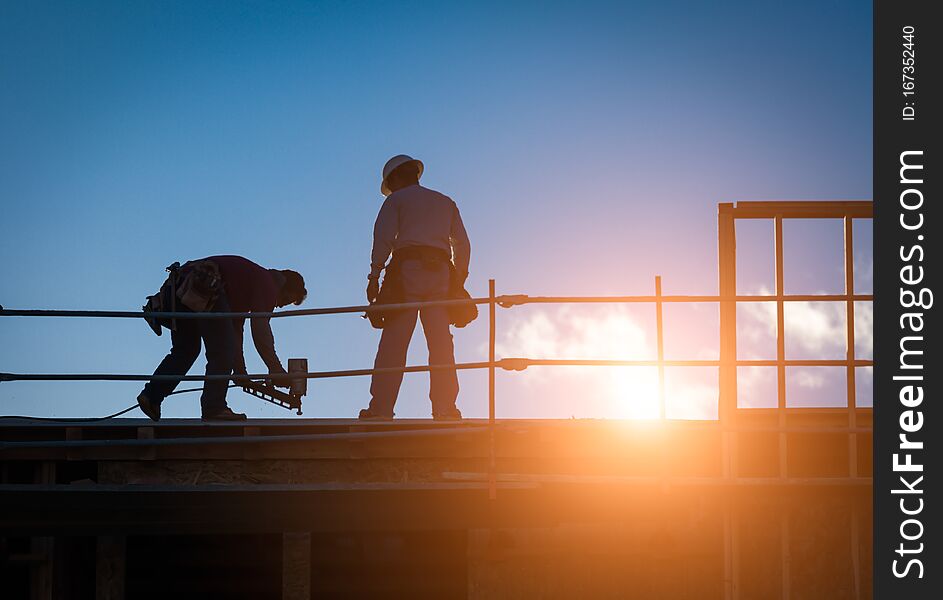 Construction Workers Silhouette on Roof of Building