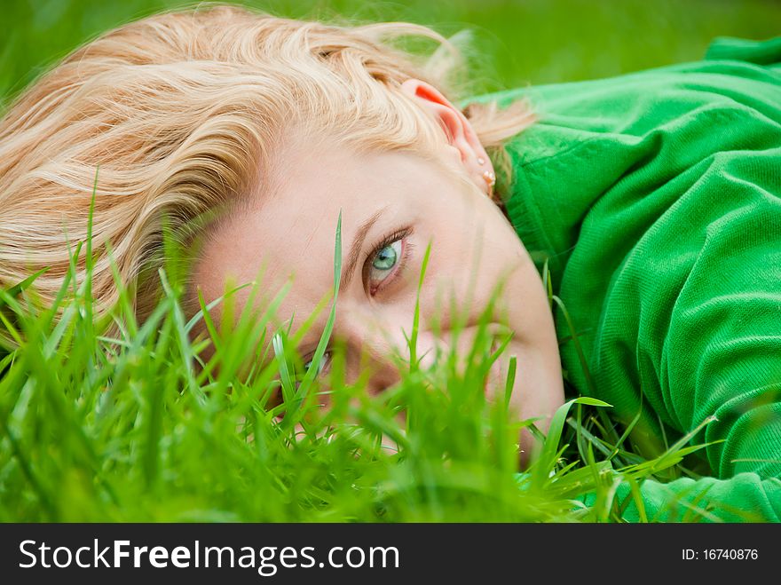 Close-up portrait of young blonde lying in a grass
