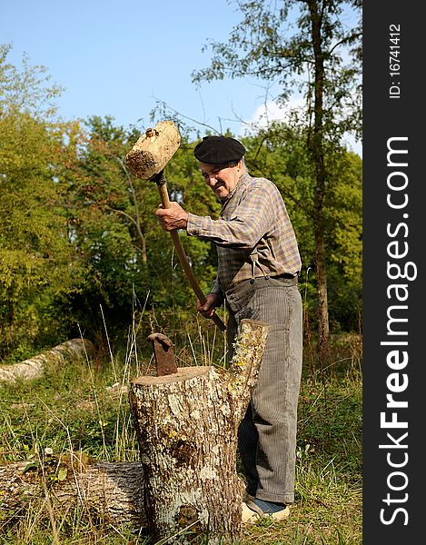 An old farmer who is splitting wood. An old farmer who is splitting wood.