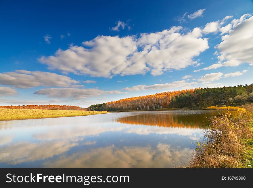 Azure lake, autumnal wood and the blue sky with clouds. Azure lake, autumnal wood and the blue sky with clouds.