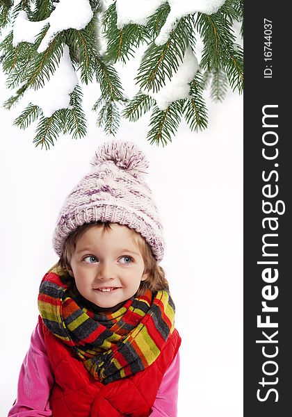 Little girl wearing winter clothes and spruce tree