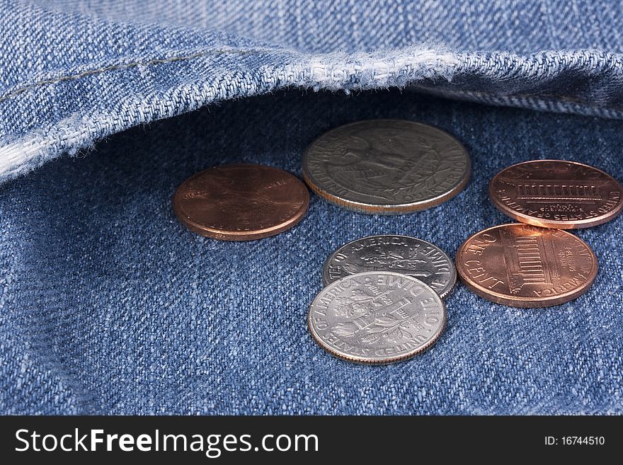 Metal coins in a pocket of dark blue jeans.