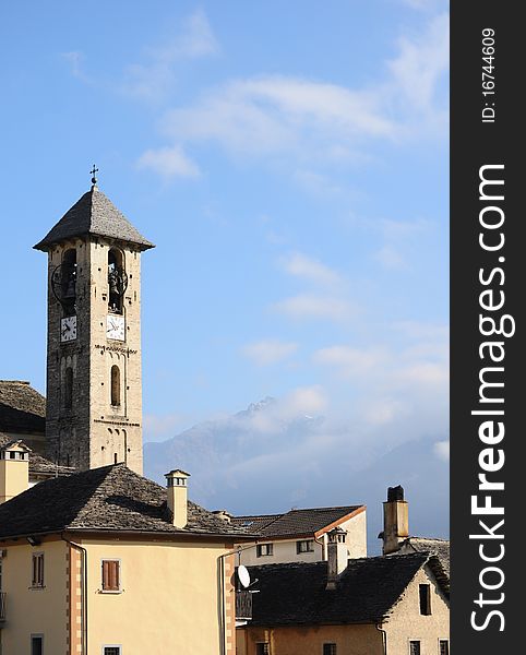 Old Italian bell tower in village with mountains in the distance. Old Italian bell tower in village with mountains in the distance