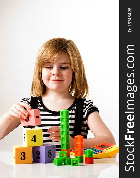 A vertical image of a young girl playing and stacking numbered building blocks. A vertical image of a young girl playing and stacking numbered building blocks