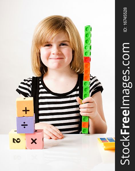 A vertical image of a young girl playing and stacking numbered building blocks. A vertical image of a young girl playing and stacking numbered building blocks