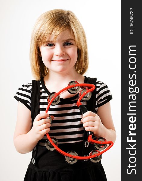 A horizontal image of a young female playinga red cresent shaped tambourine. A horizontal image of a young female playinga red cresent shaped tambourine