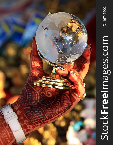 Female hand holding glass globe in sunny day.