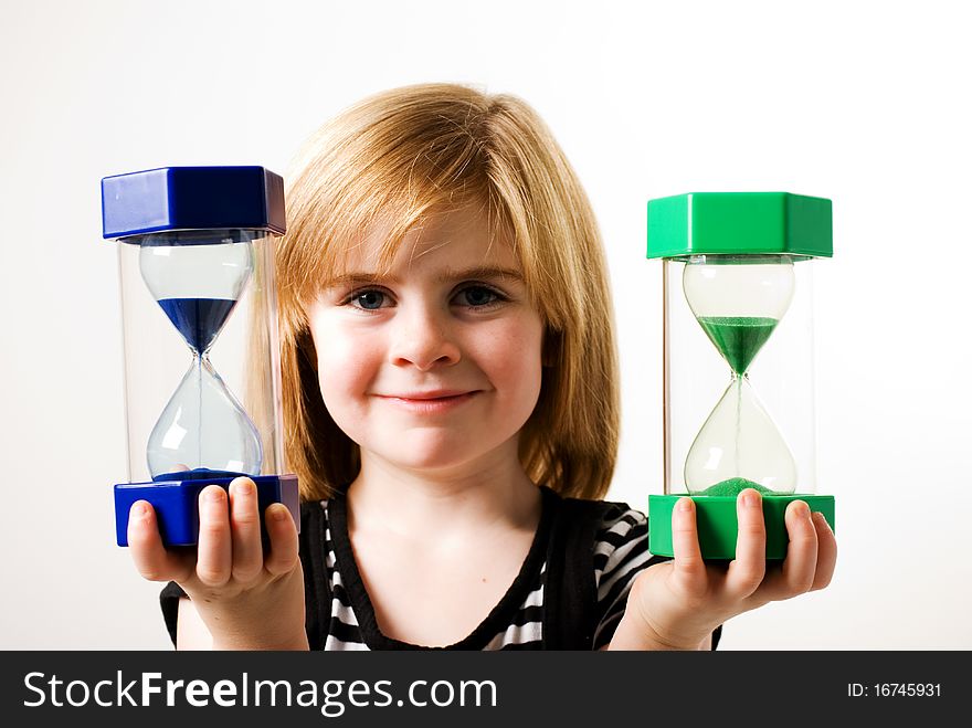 A horizontal image of a young girl looking at the sand flowing in a hourglass. A horizontal image of a young girl looking at the sand flowing in a hourglass