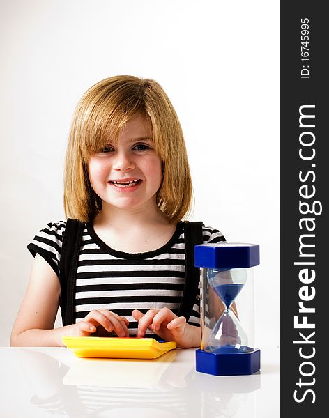 A vertical image of a young girl playing with a calculator and hourglass. A vertical image of a young girl playing with a calculator and hourglass