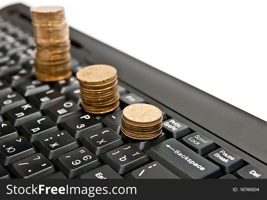 Line of coins on black computer keyboard. Isolated on white. Line of coins on black computer keyboard. Isolated on white