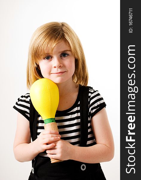 A vertical image of a young girl with a large musical shaker. A vertical image of a young girl with a large musical shaker