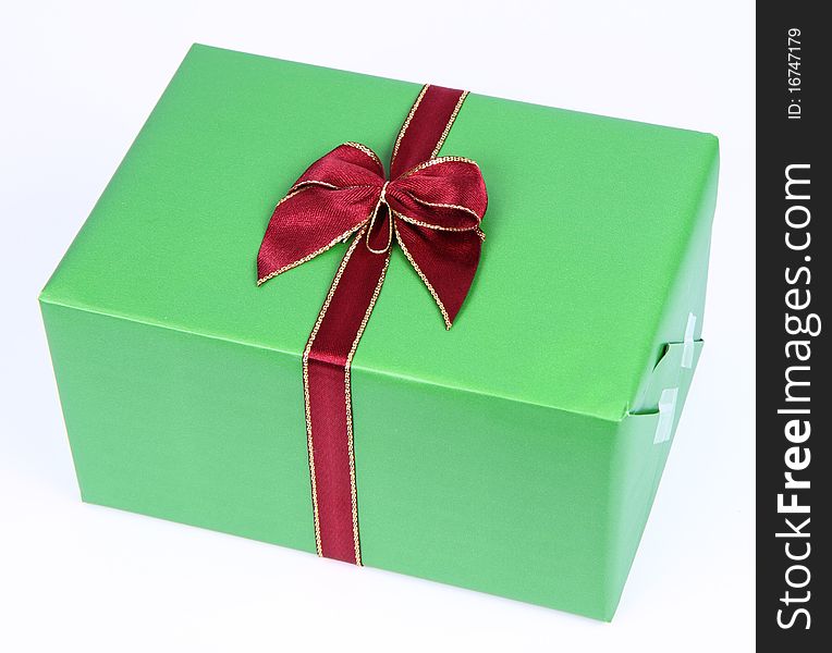 Gift in green wrapping with a red bow on white background