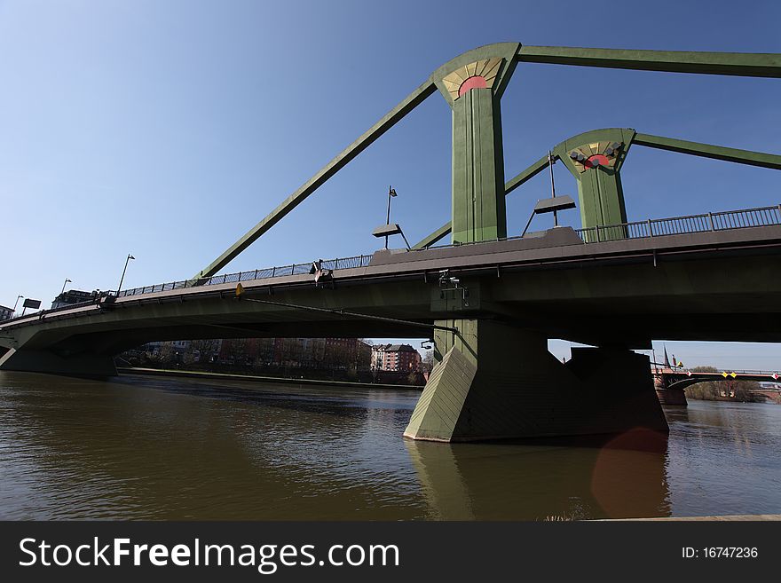 Flößerbrücke is a 221 meters long bridge over the Main river in Frankfurt am Main, Germany.In the background can be seen the skyline of Frankfurt. Flößerbrücke is a 221 meters long bridge over the Main river in Frankfurt am Main, Germany.In the background can be seen the skyline of Frankfurt.