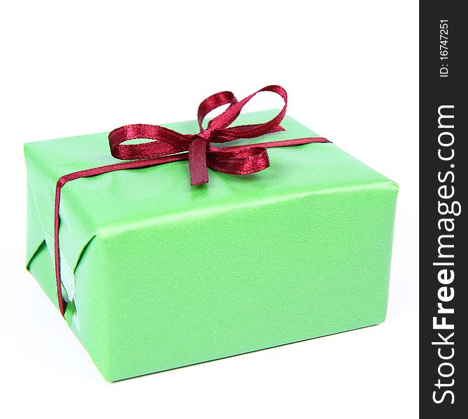 Gift in green wrapping with a red bow on white background