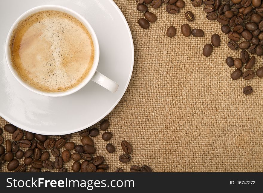 Burlap, canvas as a backdrop, coffee beans as a frame, and a cup of coffee