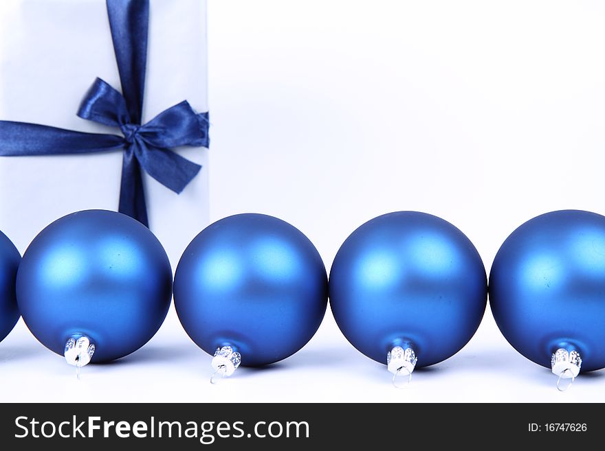 Blue matt christmas balls and a gift in red wrapping on white background, with space for your text. Blue matt christmas balls and a gift in red wrapping on white background, with space for your text