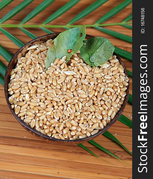 Bowl of hybrid wheat seeds on wooden background.