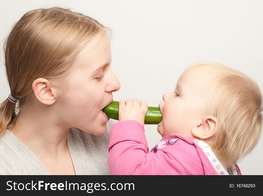 Mother with daughter eat cucumber