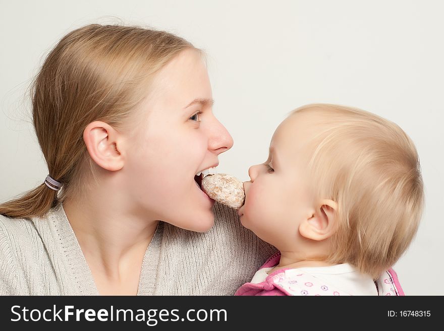 Young mother with toddler daughter eat and bitting gingerbread. Young mother with toddler daughter eat and bitting gingerbread