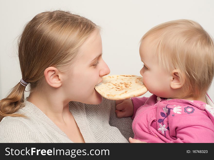 Young mother with toddler daughter eat and bitting flatbread. Young mother with toddler daughter eat and bitting flatbread