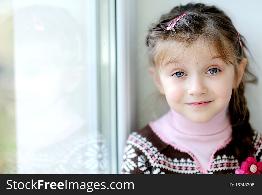 Beauty small girl with long dark braid and big blue eyes in winter sweater