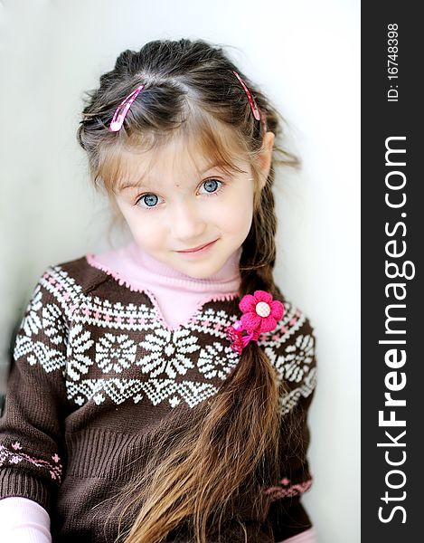 Beauty small girl with long dark braid and big blue eyes in winter sweater