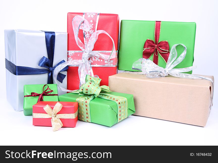 Gifts in silver, green, brown and red wrapping with bows on white background. Gifts in silver, green, brown and red wrapping with bows on white background