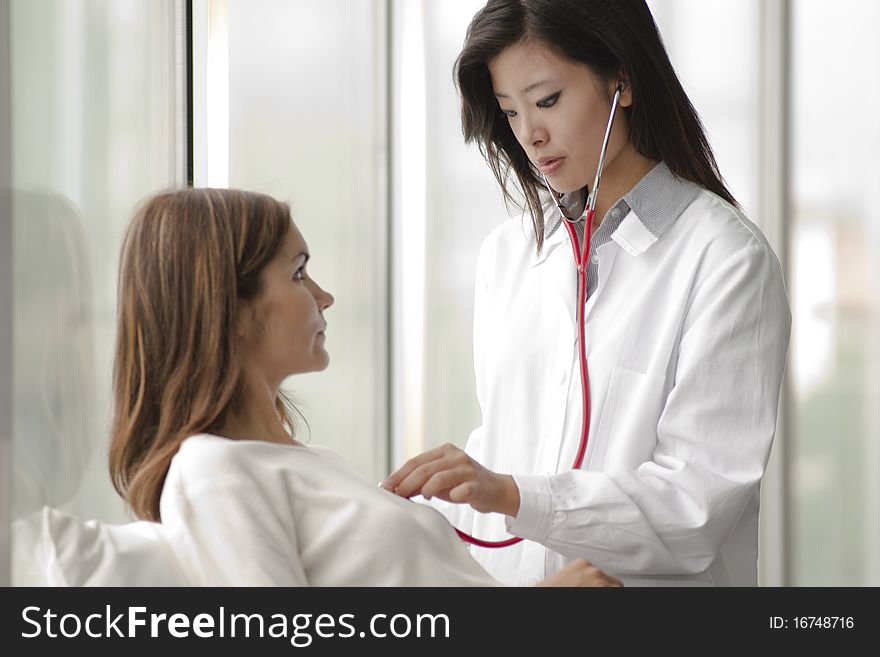 Female doctor checking patient's heart with stethoscope. Female doctor checking patient's heart with stethoscope
