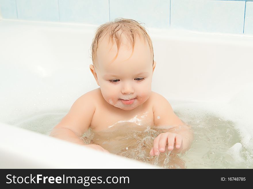 Cute adorable baby clapping on water in foam bath